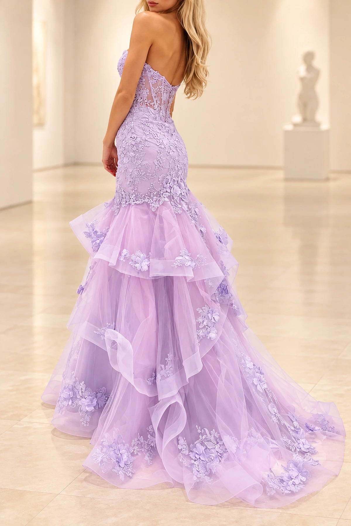 Back view of lavender strapless mermaid prom dress featuring a low V back, intricate floral lace appliques, and cascading layered tulle ruffles by Graceprom.