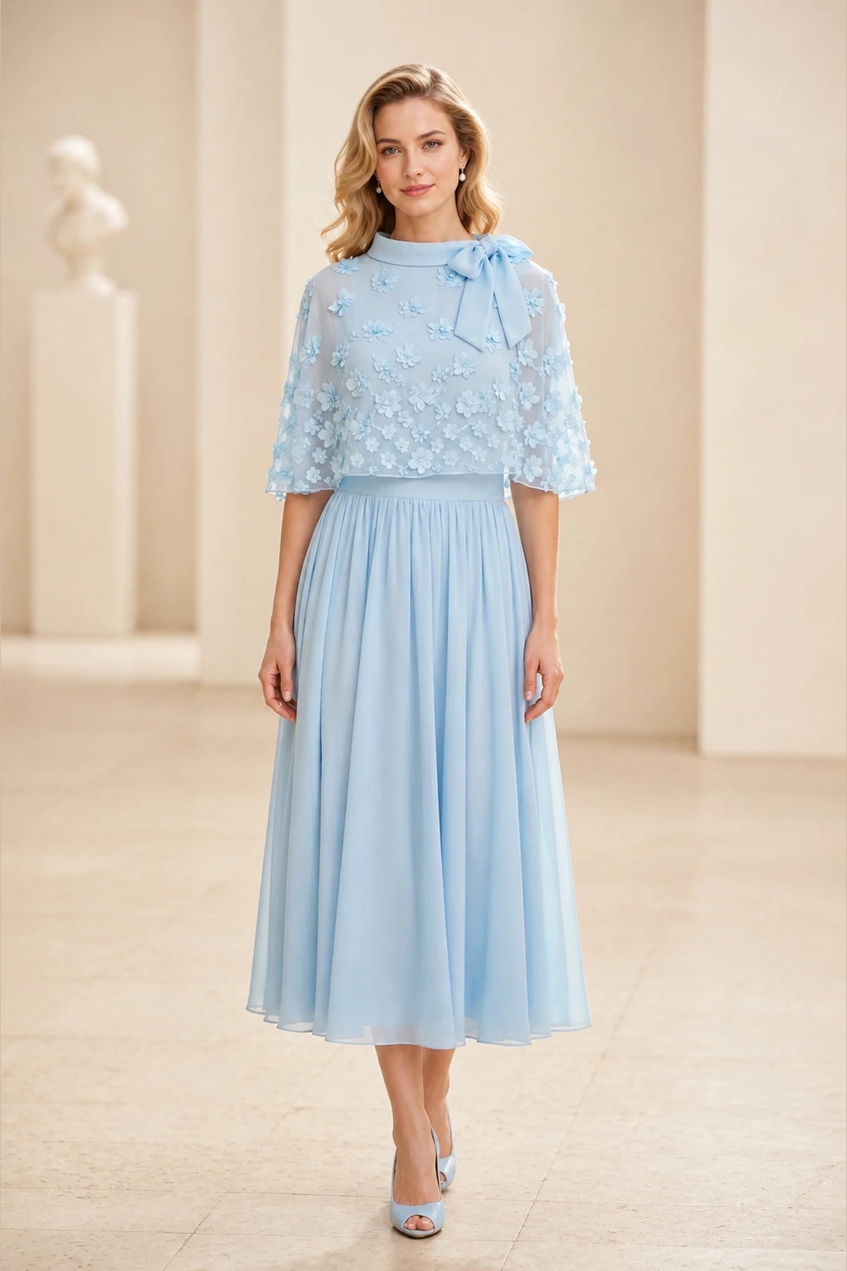 Light blue mother of the bride dress with high neckline, sheer floral cape sleeves and tea-length A-line skirt