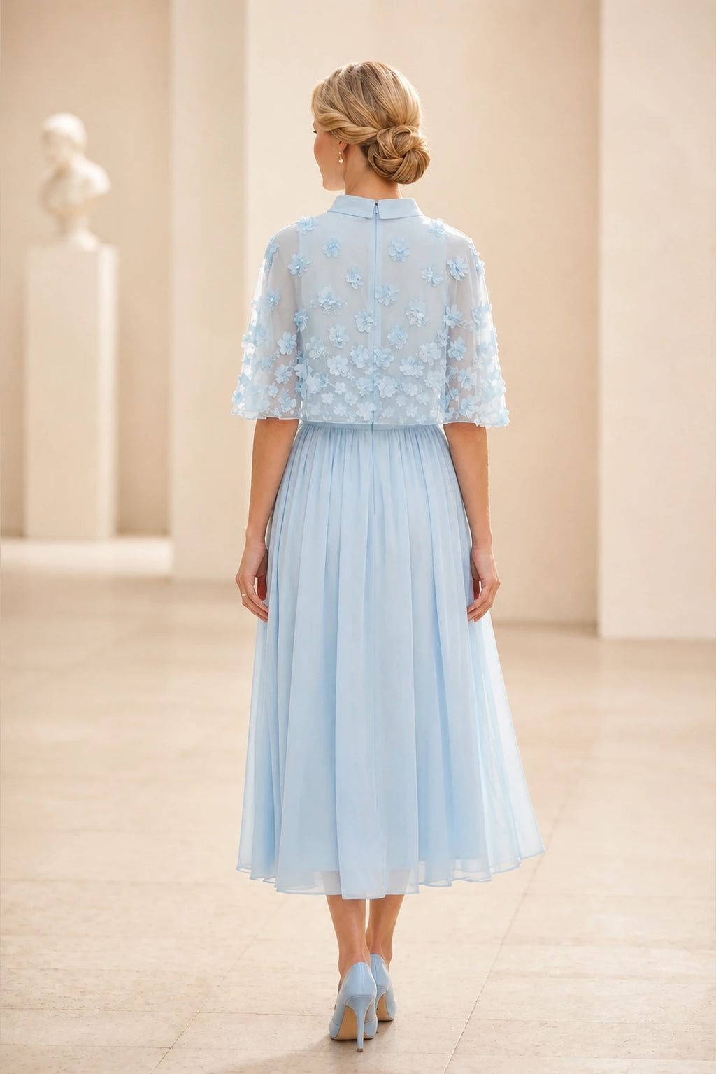 Back view of light blue mother of the bride dress with sheer floral cape, center zipper and tea-length A-line skirt