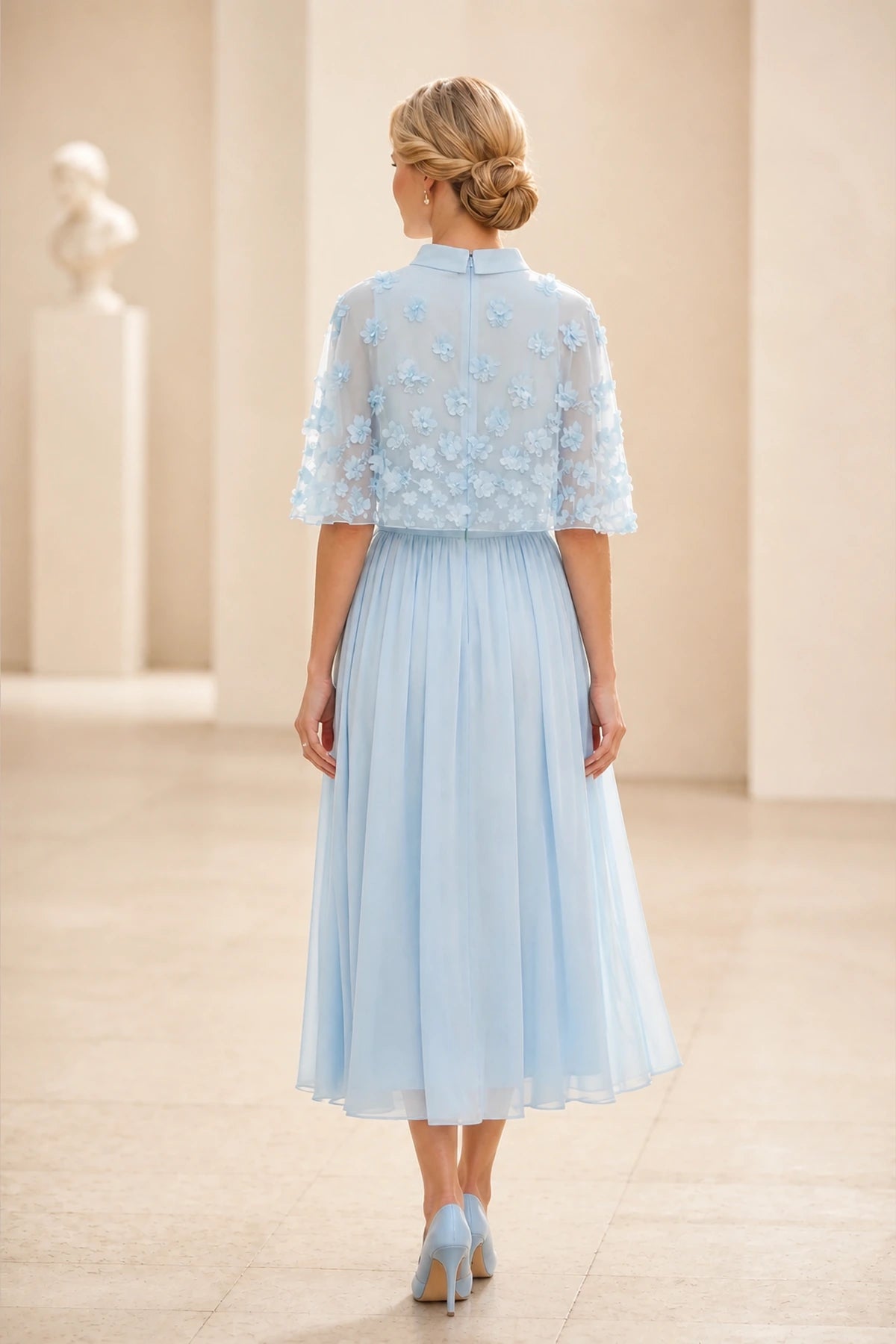 Back view of light blue mother of the bride dress with sheer floral cape, center zipper and tea-length A-line skirt