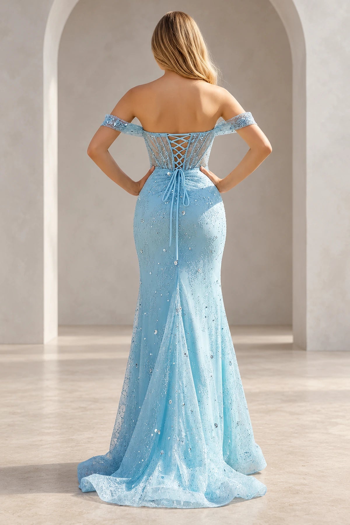 Light blue embellished prom dress with a low sheer back, crisscross lacing tied at the waist, fitted skirt, and flowing train.