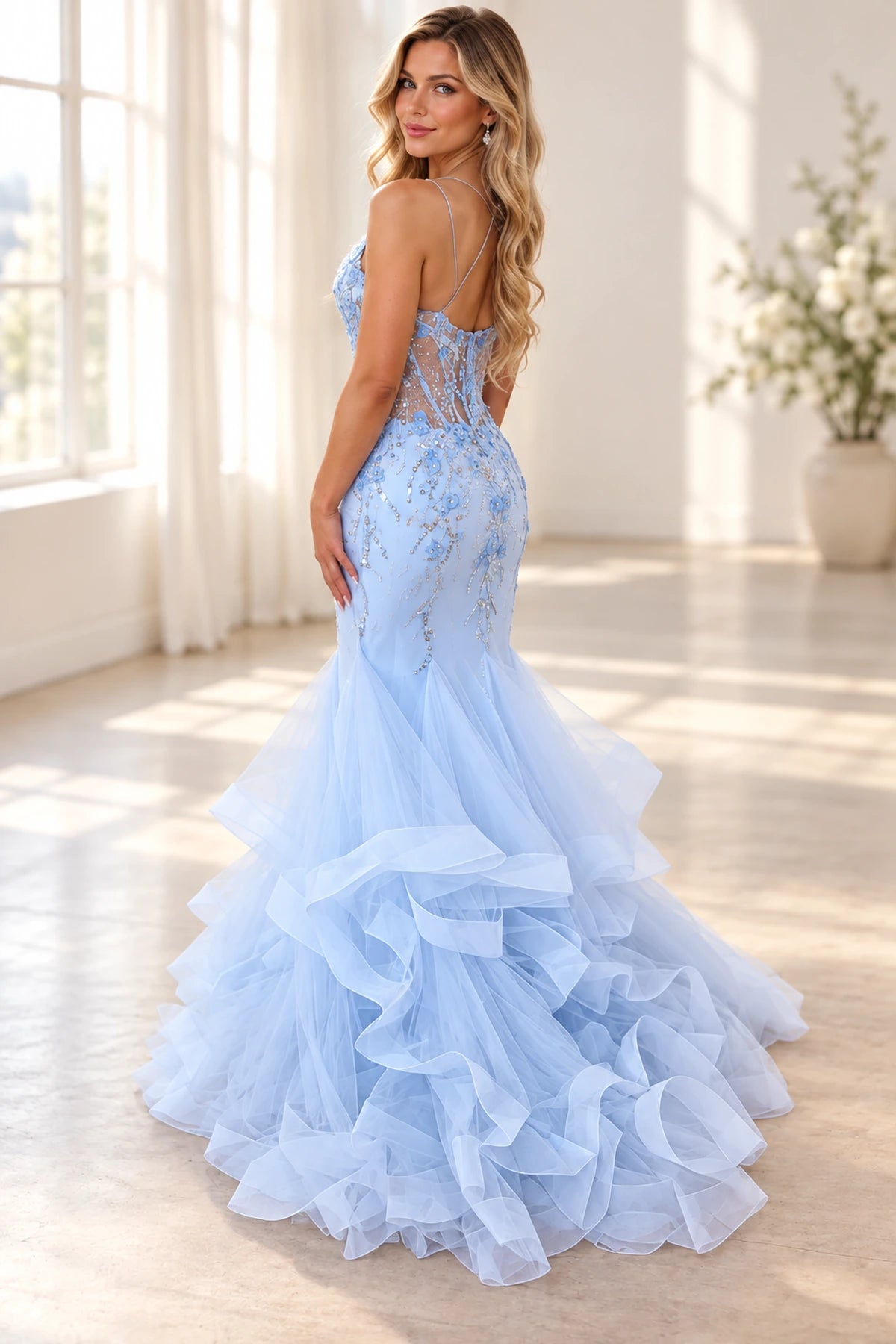 Back view of light blue mermaid prom dress featuring a sheer lace illusion back, thin straps, intricate beadwork, and layered floor-length tulle ruffles.