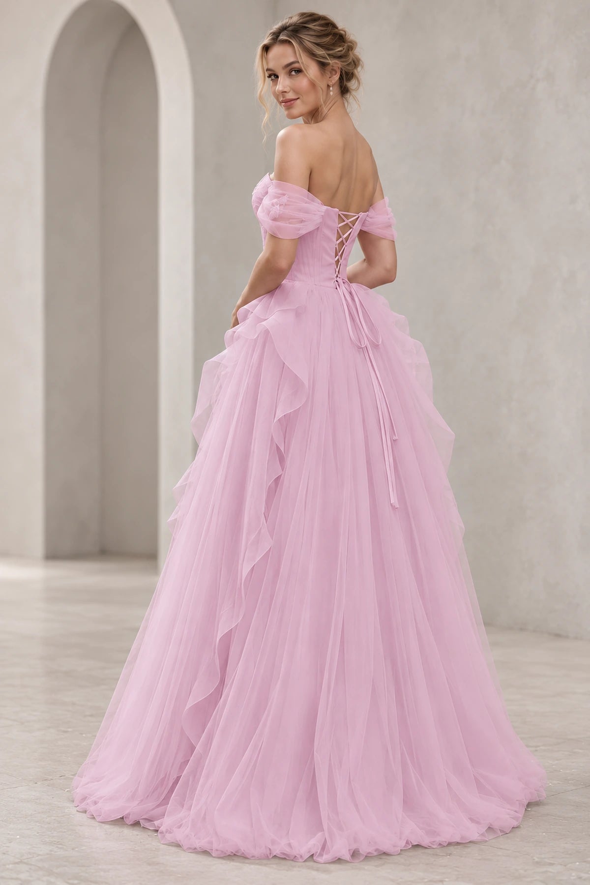 Back view of light pink tulle prom dress featuring off-the-shoulder sleeves, crisscross lace-up corset back, long tie ribbons, and layered A-line tulle skirt.