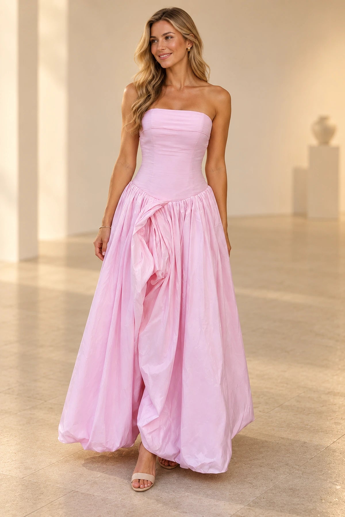 Light pink strapless A-line prom dress with straight neckline, ruched fitted bodice, draped front slit and flowing skirt by Graceprom