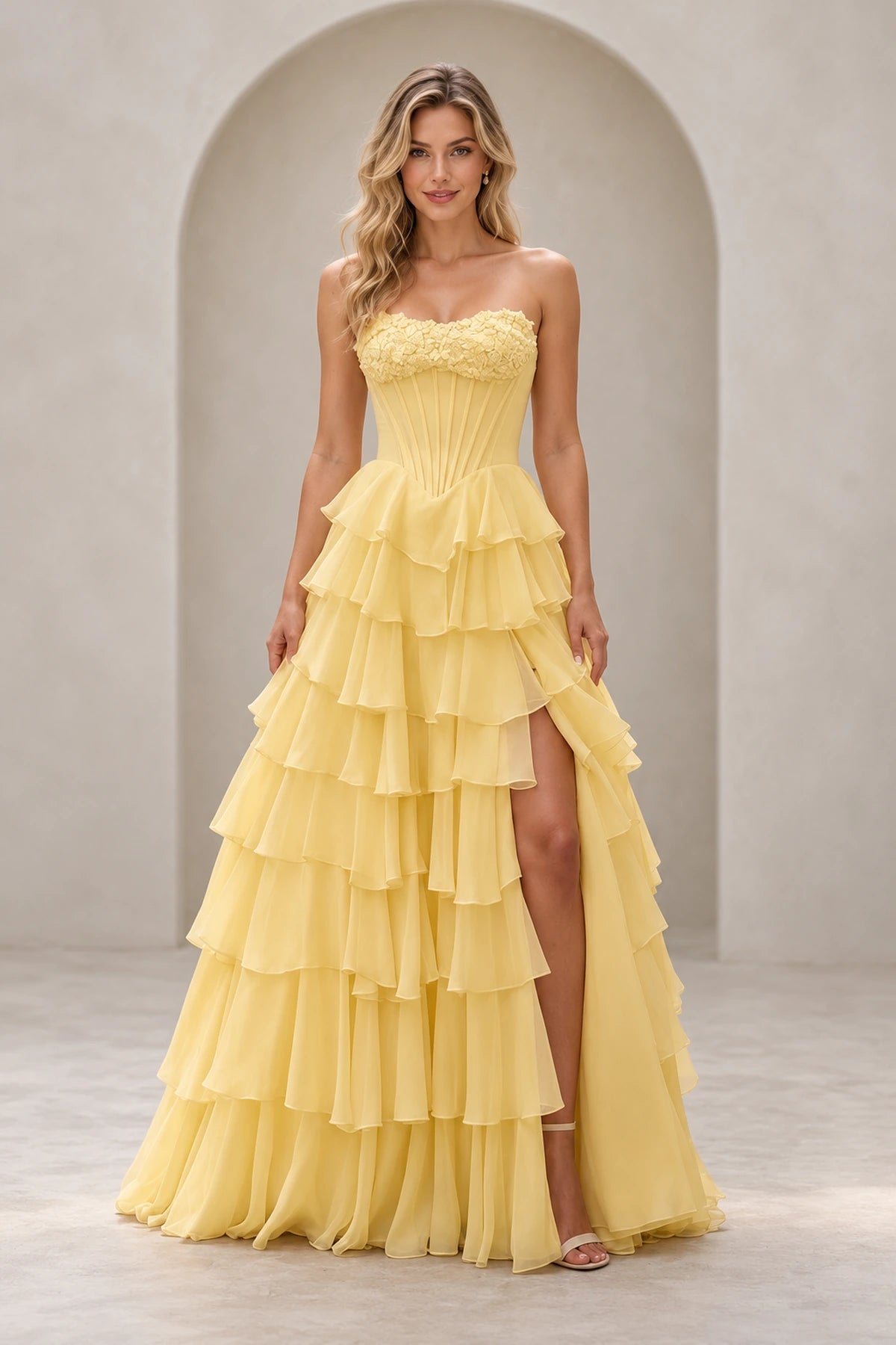 Light yellow strapless A line prom dress with floral sweetheart neckline, pointed corset-style bodice, tiered ruffle skirt, and high slit.