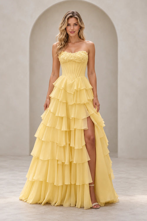 Light yellow strapless A line prom dress with floral sweetheart neckline, pointed corset-style bodice, tiered ruffle skirt, and high slit.