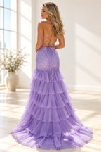 Back view of a lilac mermaid prom dress featuring an open lace-up back, bow ties, tiered ruffles, and sweeping train.