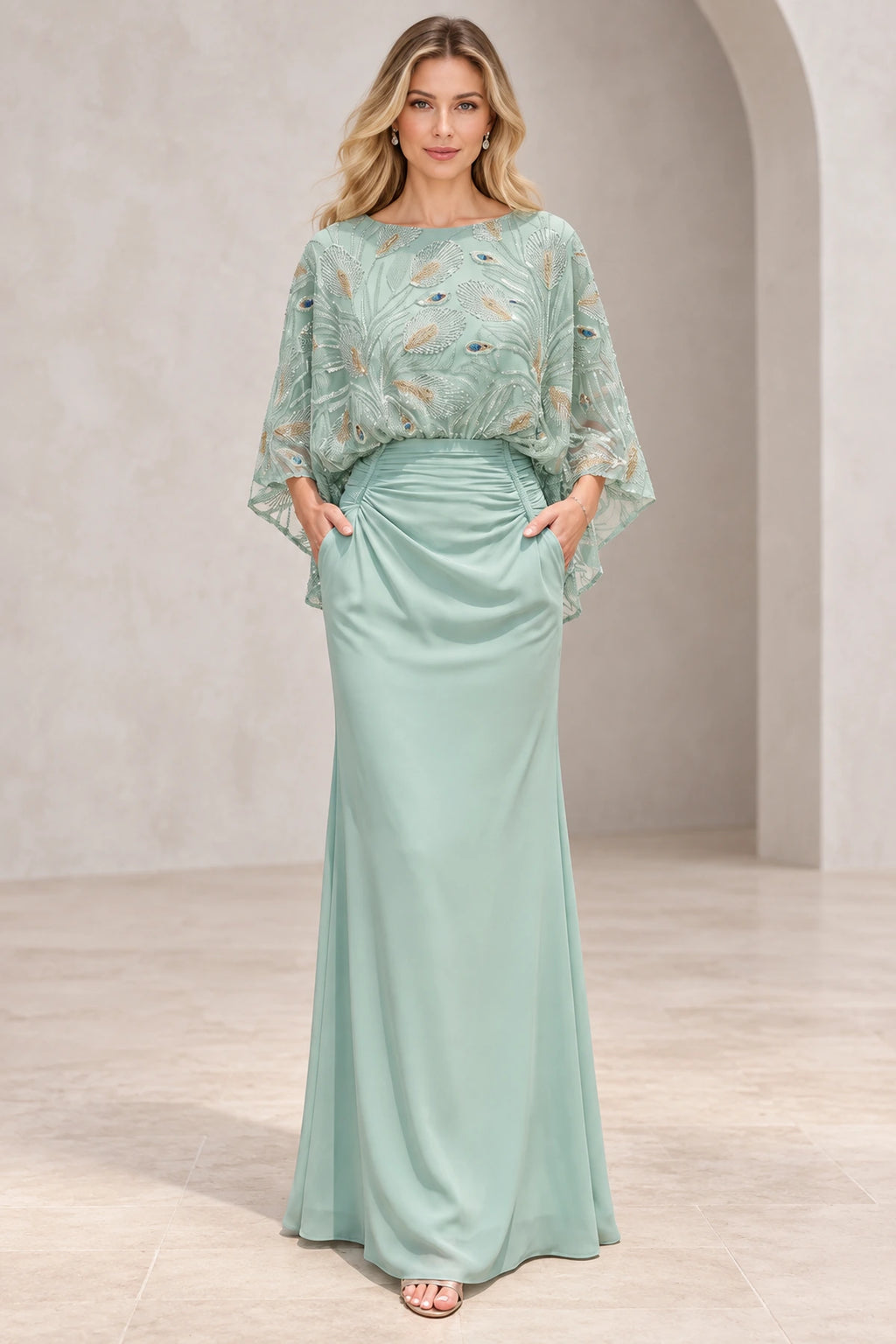Mint green mother of the bride dress with bateau neckline embellished cape sleeves ruched waist and fitted floor-length silhouette