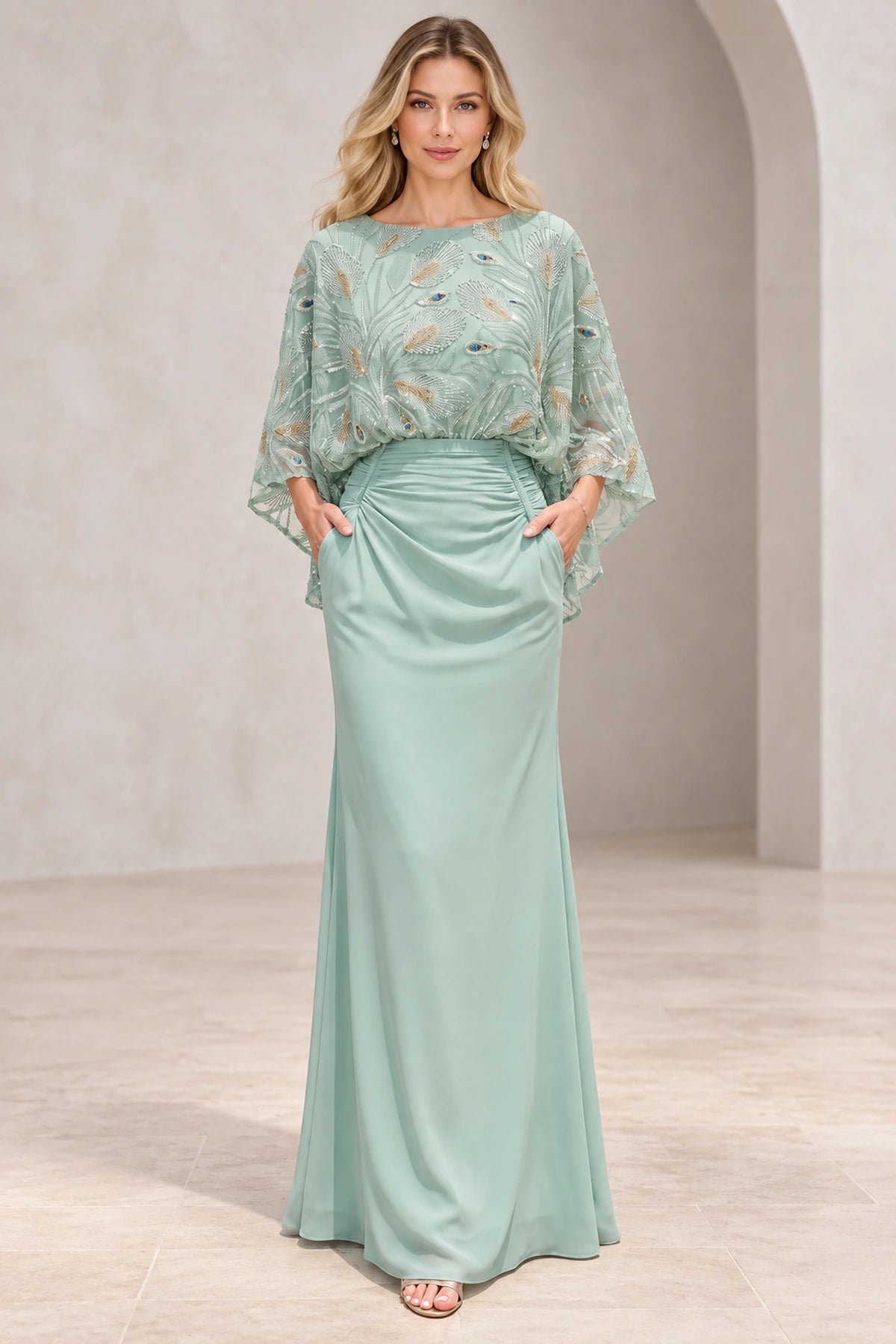 Mint green mother of the bride dress with bateau neckline embellished cape sleeves ruched waist and fitted floor-length silhouette