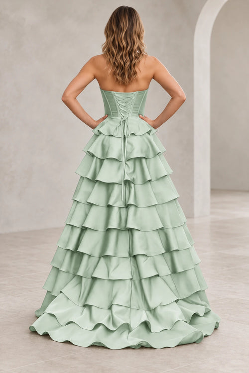 Back view of a mint green prom dress with matching corset lacing, a waist bow with long ties, and cascading ruffle tiers.
