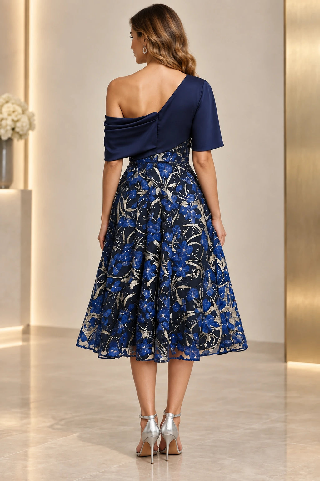 Back view of navy floral Mother of the Bride Dress with draped asymmetrical shoulder and full tea-length skirt