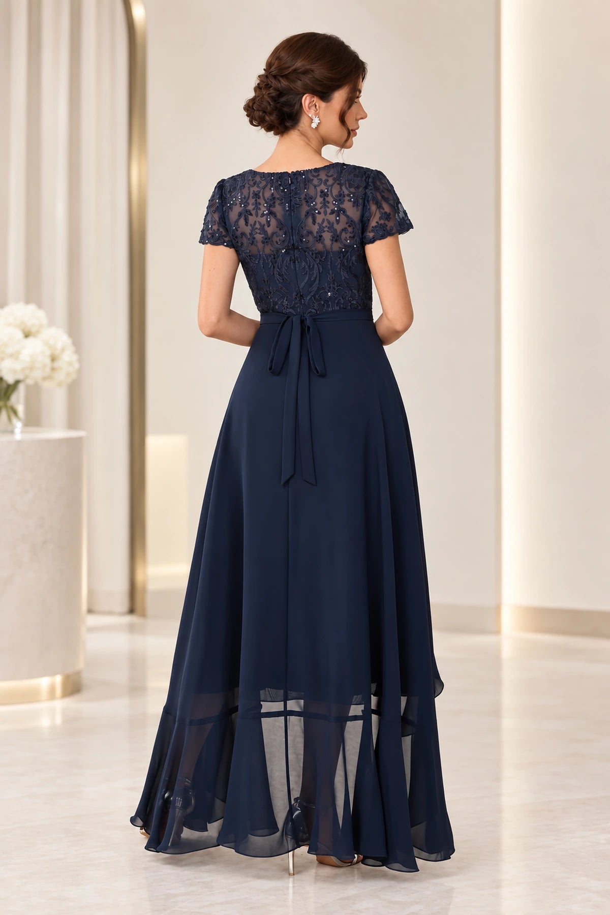 Back view of navy mother of the bride dress with sheer lace back short sleeves waist tie and high low skirt