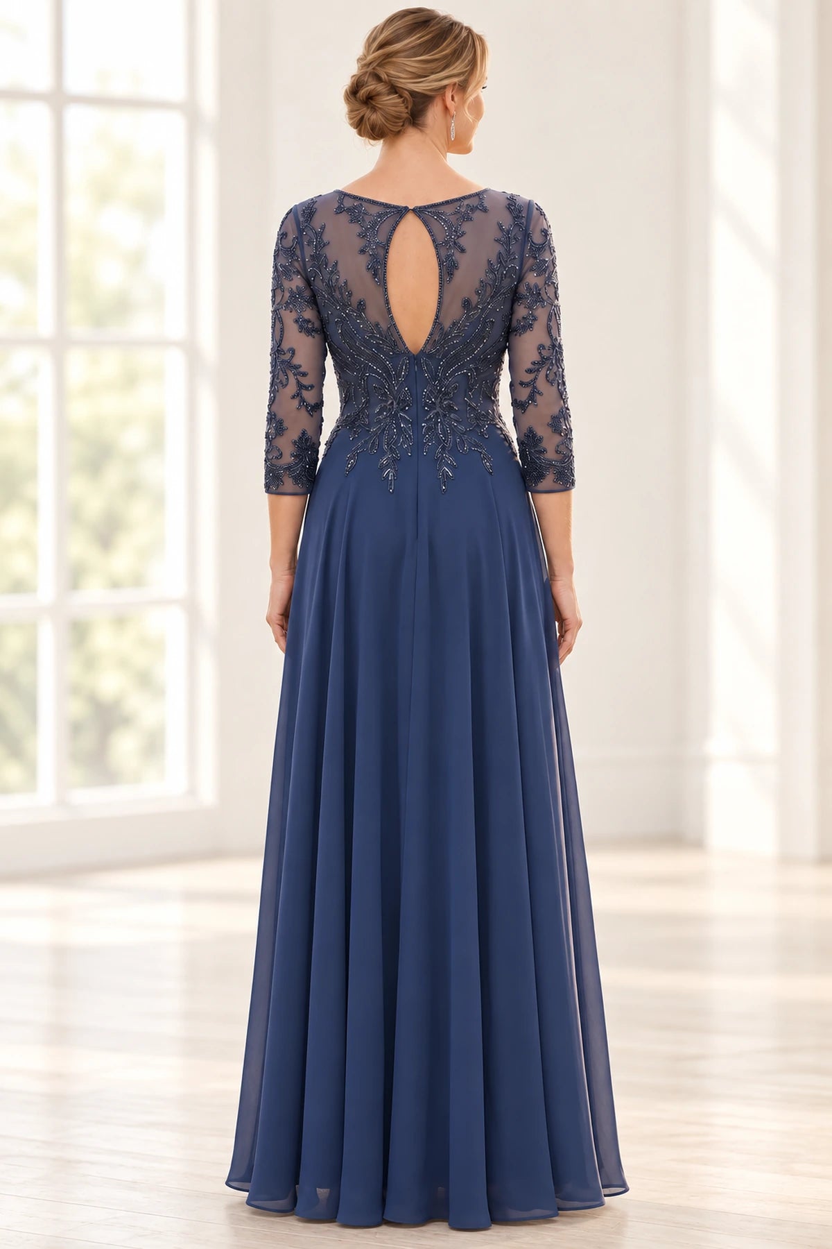 Back view of navy mother of the bride dress with sheer embroidered back, keyhole opening, three-quarter sleeves, and flowing floor-length skirt