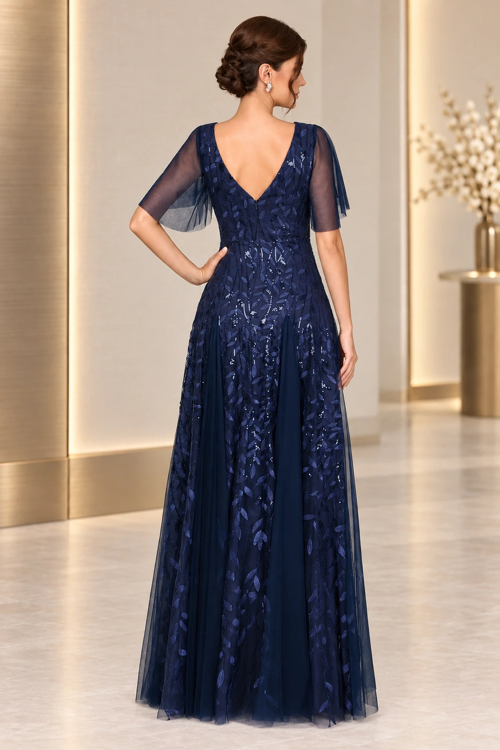 Back view of navy mother of the bride dress with V back flutter sleeves sequined overlay and long A-line skirt