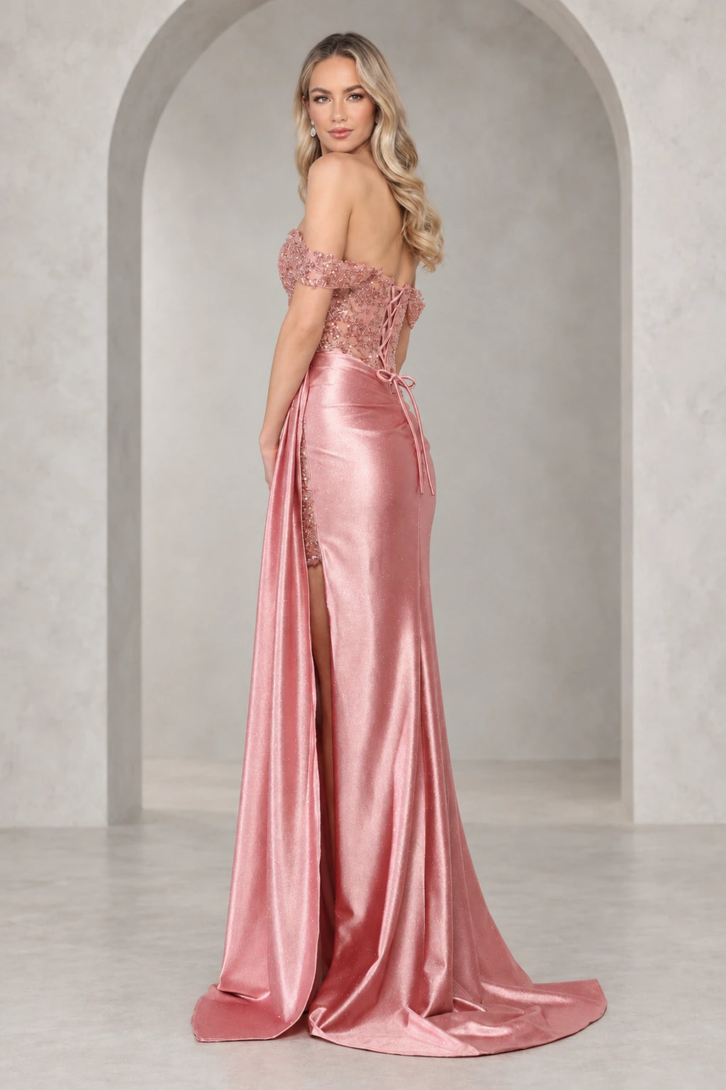 Back view of a rose prom dress with an embellished lace-up bodice, long matching ties, fitted shimmering skirt, and short train.
