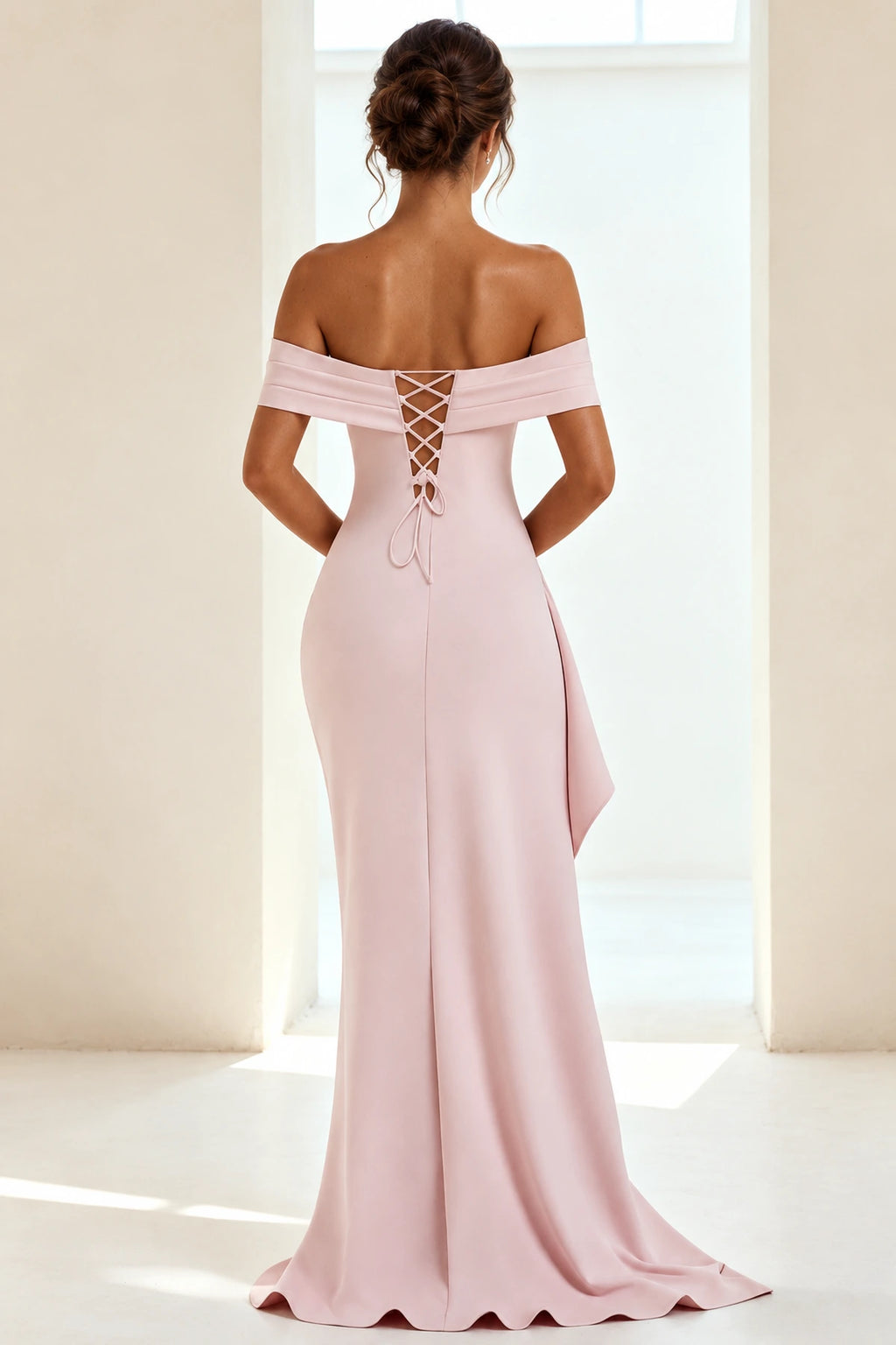 Back view of blush pink off-the-shoulder prom dress featuring a lace-up corset closure, fitted sheath silhouette and floor-length skirt.