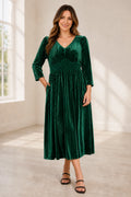 Plus size emerald green velvet mother of the bride dress with V neckline long sleeves and pleated tea length skirt