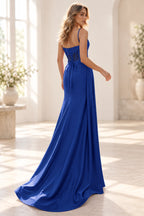Royal blue prom dress showing a low lace-up back, floral embellished sheer panels, waist bow, and flowing train.