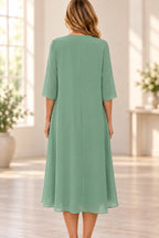 Back view of sage green Mother of the Bride Dress with closed back, half sleeves and flowing tea-length layered skirt