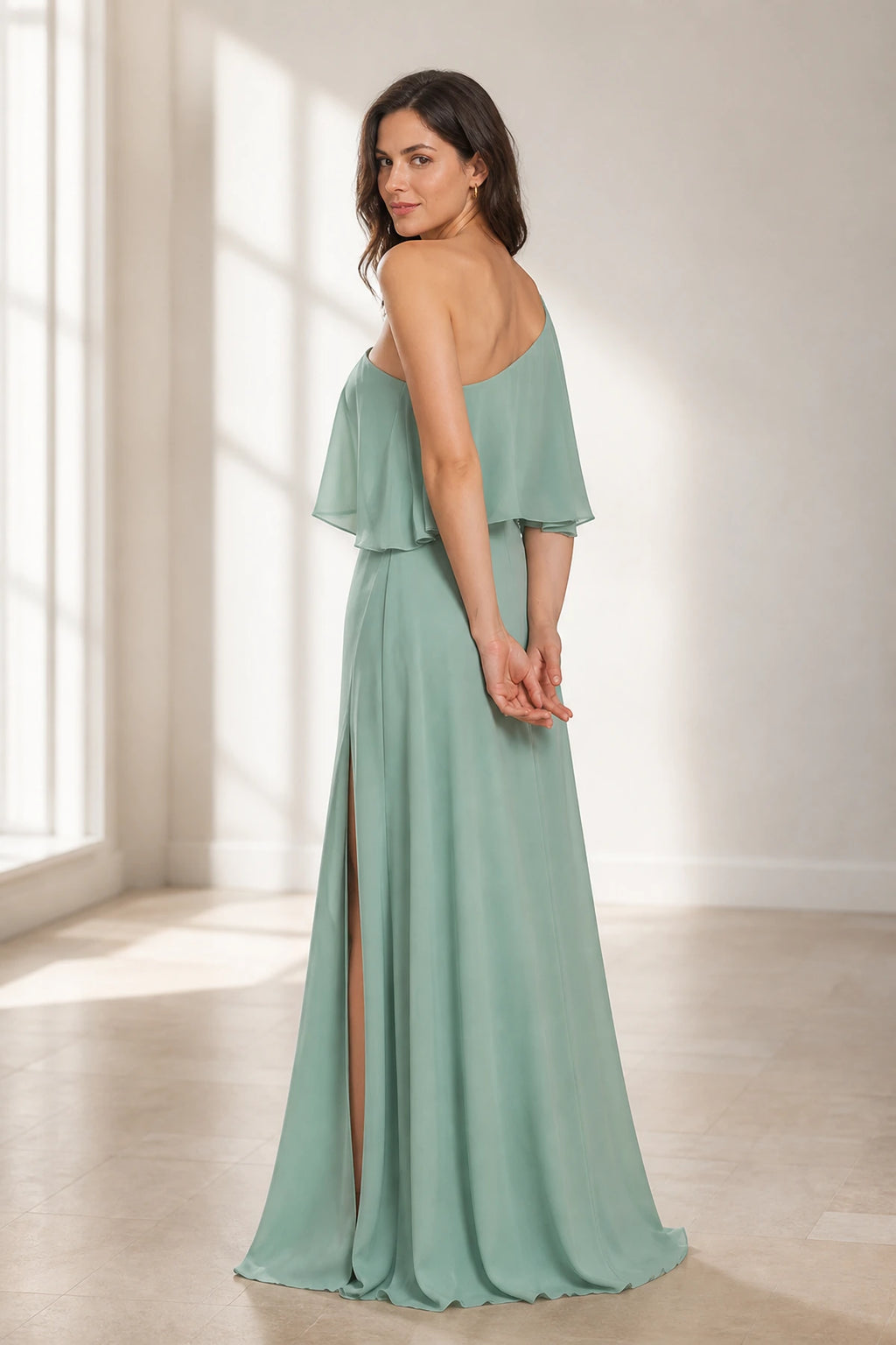 Sage green floor-length wedding guest dress with asymmetric one-shoulder back and flowing ruffle overlay back view