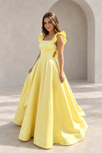 Light yellow satin A-line prom dress with square neckline, ruffle cap sleeves, fitted waist and voluminous floor length pleated skirt by Graceprom