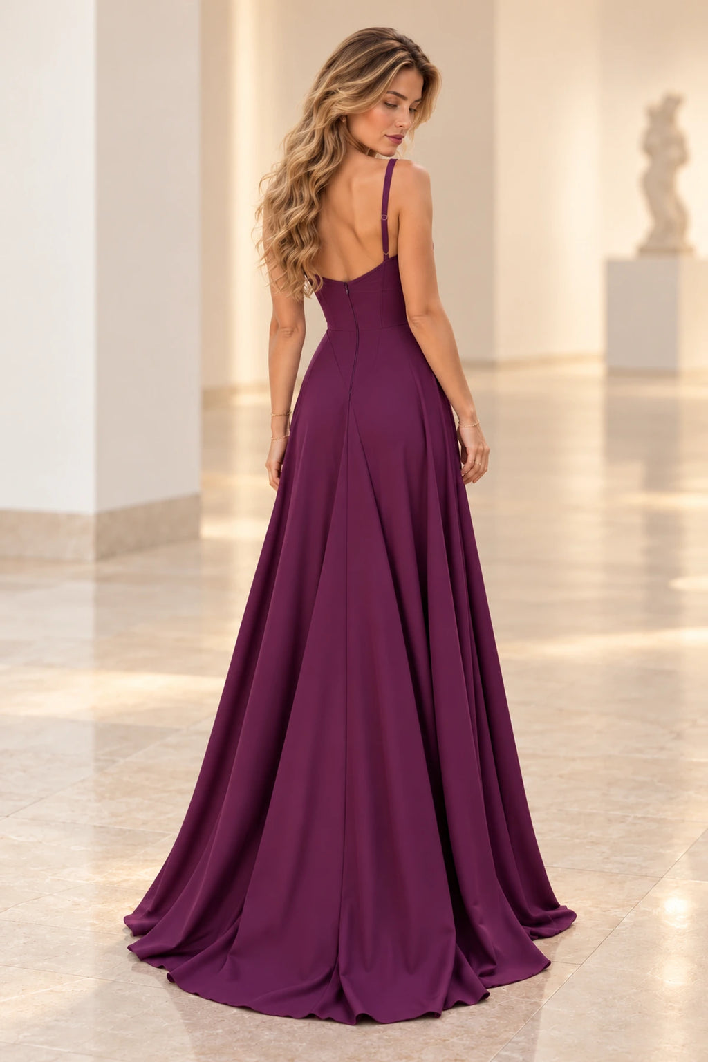 Back view of plum purple satin bridesmaid dress featuring low V back, spaghetti straps, center zipper, fitted waist and flowing A-line skirt