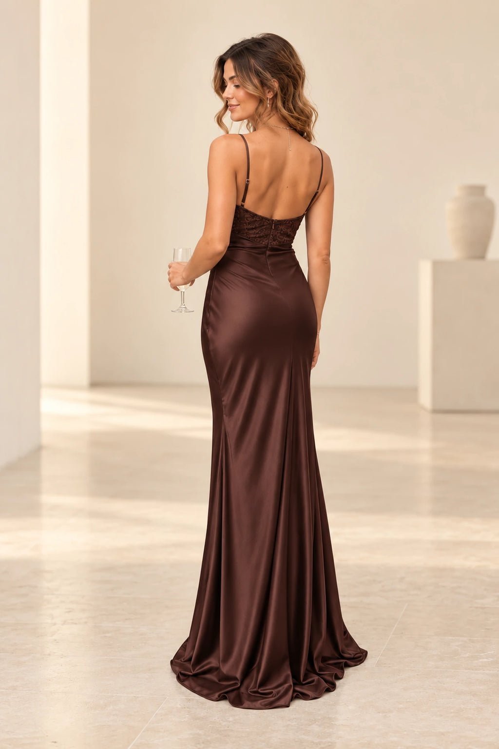 Back view of chocolate brown satin mermaid evening dress featuring spaghetti straps, low back, floral lace bodice, center zipper and flowing skirt