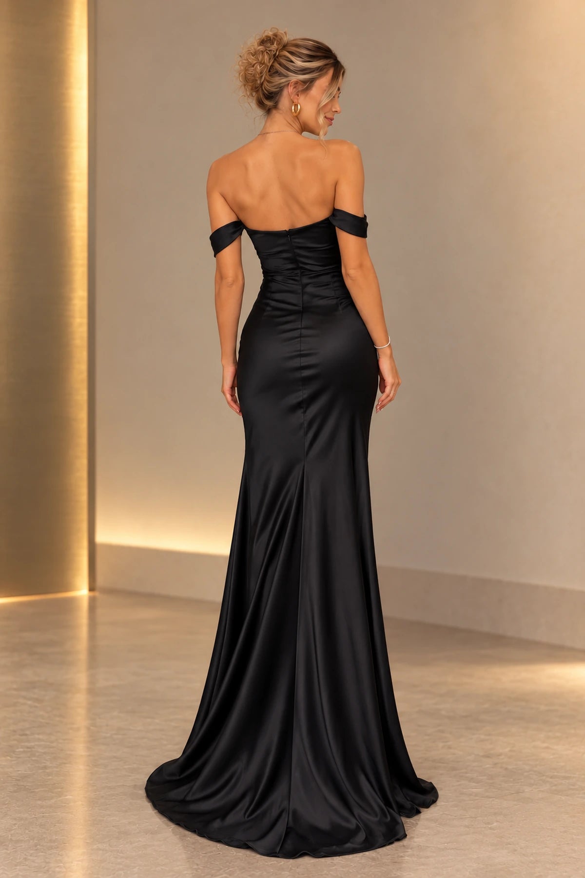 Back view of black satin mermaid prom dress featuring off shoulder bands, low straight back, center zipper, fitted waist and flared floor length skirt