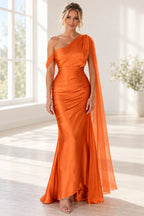 Front view of an orange Graceprom satin prom dress with a pleated one-shoulder bodice, fitted skirt and long bead-accented sheer cape drape.