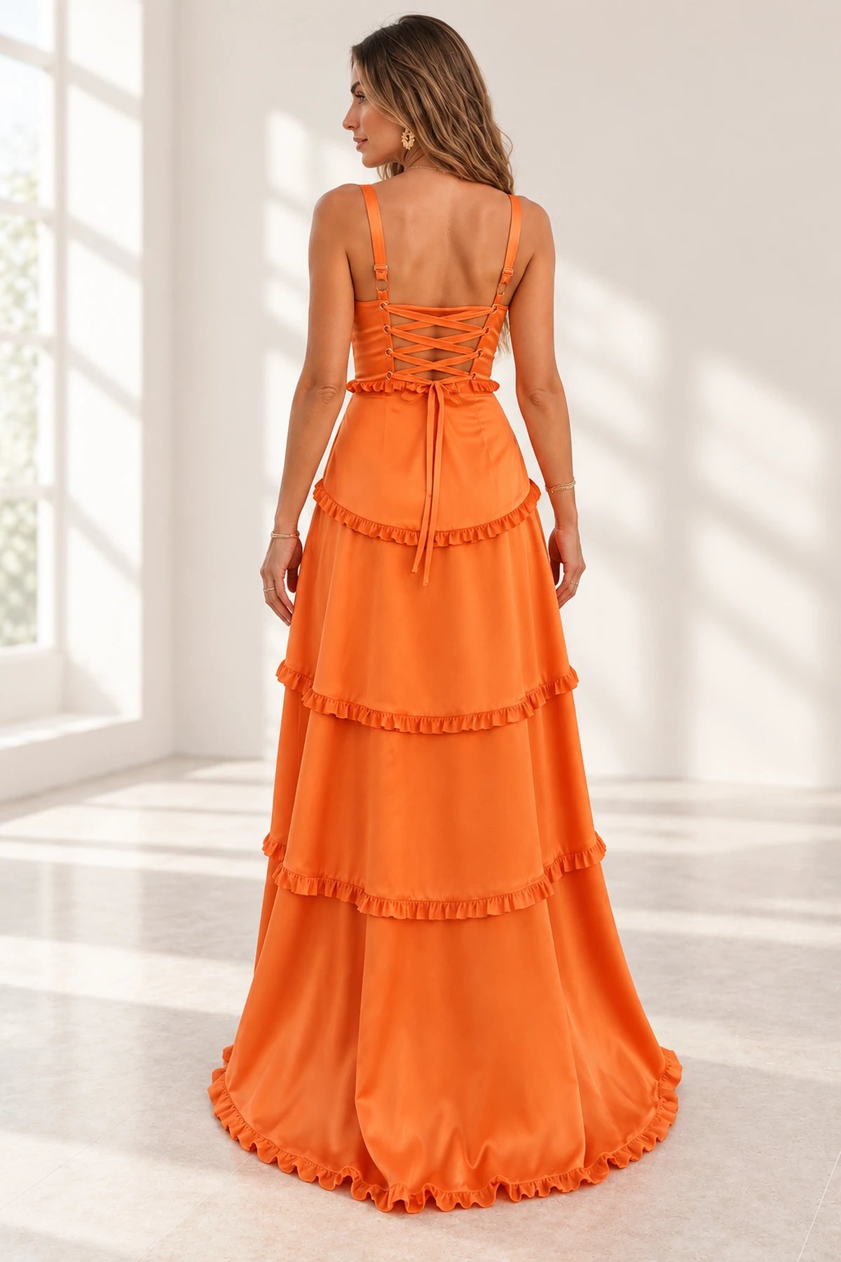 Back view of an orange Graceprom satin prom dress with adjustable straps, ribbon lace-up detailing and a tiered floor-length ruffle skirt.