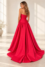 Back view of red satin prom dress featuring straight strapless back, vertical bodice seams, fitted drop waist and flowing full A-line skirt