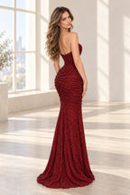 Back view of a burgundy sequin prom gown featuring a low back, ruched fitted silhouette, sparkling texture, and floor-length mermaid skirt.