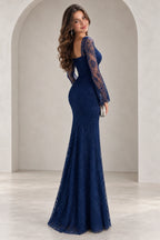 Back view of Graceprom navy blue sequin prom dress with a low back, ruched waist and hips, sheer long sleeves and a flared skirt.
