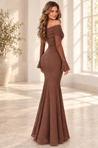 Back view of a sequin mermaid wedding guest dress with draped off shoulder back, long sleeves, and a fitted floor length silhouette.
