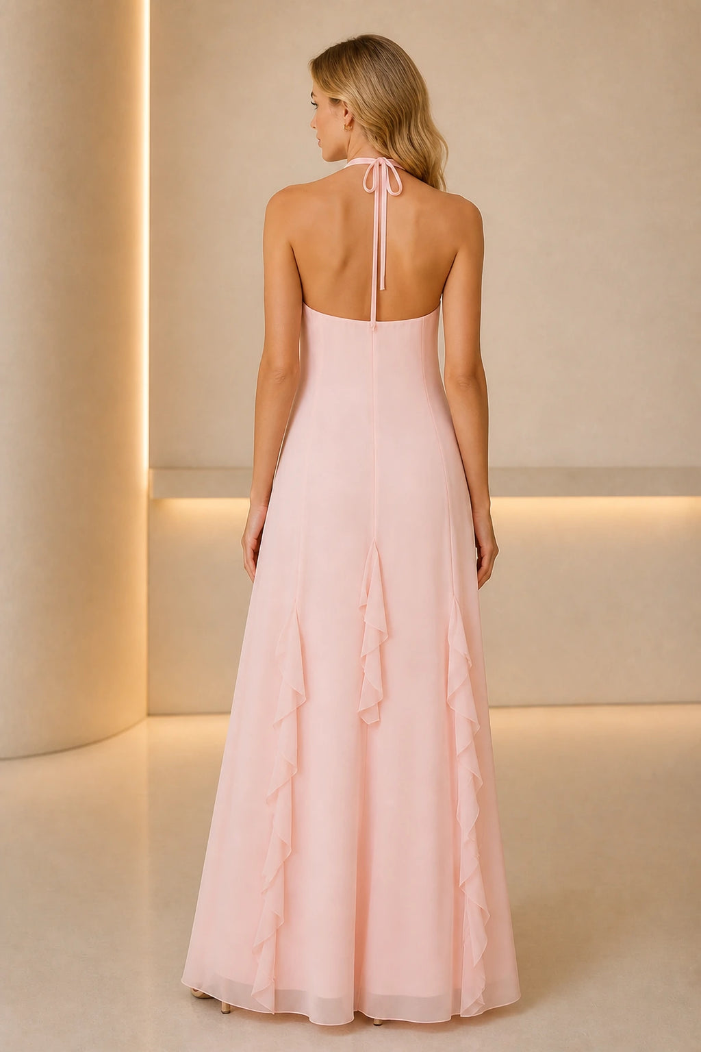 Back view of soft pink wedding guest dress with halter tie, open back and flowing floor-length A-line skirt