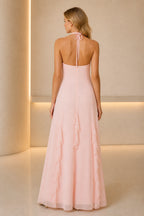Back view of soft pink wedding guest dress with halter tie, open back and flowing floor-length A-line skirt