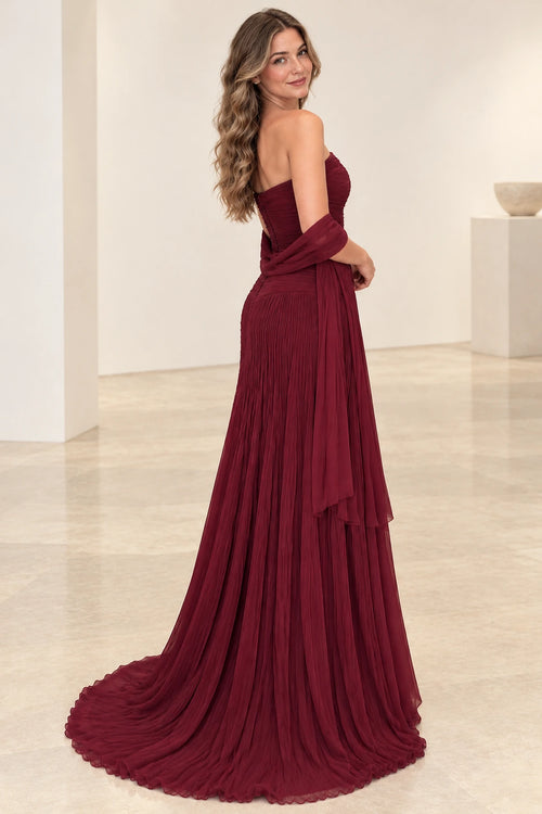 Back view of Graceprom burgundy chiffon wedding guest dress with a low strapless back, covered button detailing and flowing pleated train.