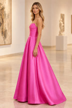 Side view of a fuchsia strapless satin prom dress showing the fitted bodice, defined waist, and flared floor-length A-line skirt.