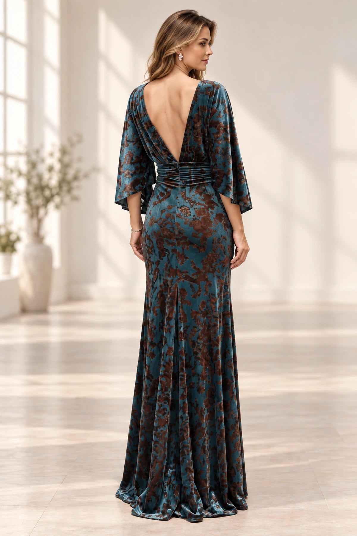 Back view of teal floral mother of the bride dress with deep V low back cape sleeves ruched waist and floor-length skirt