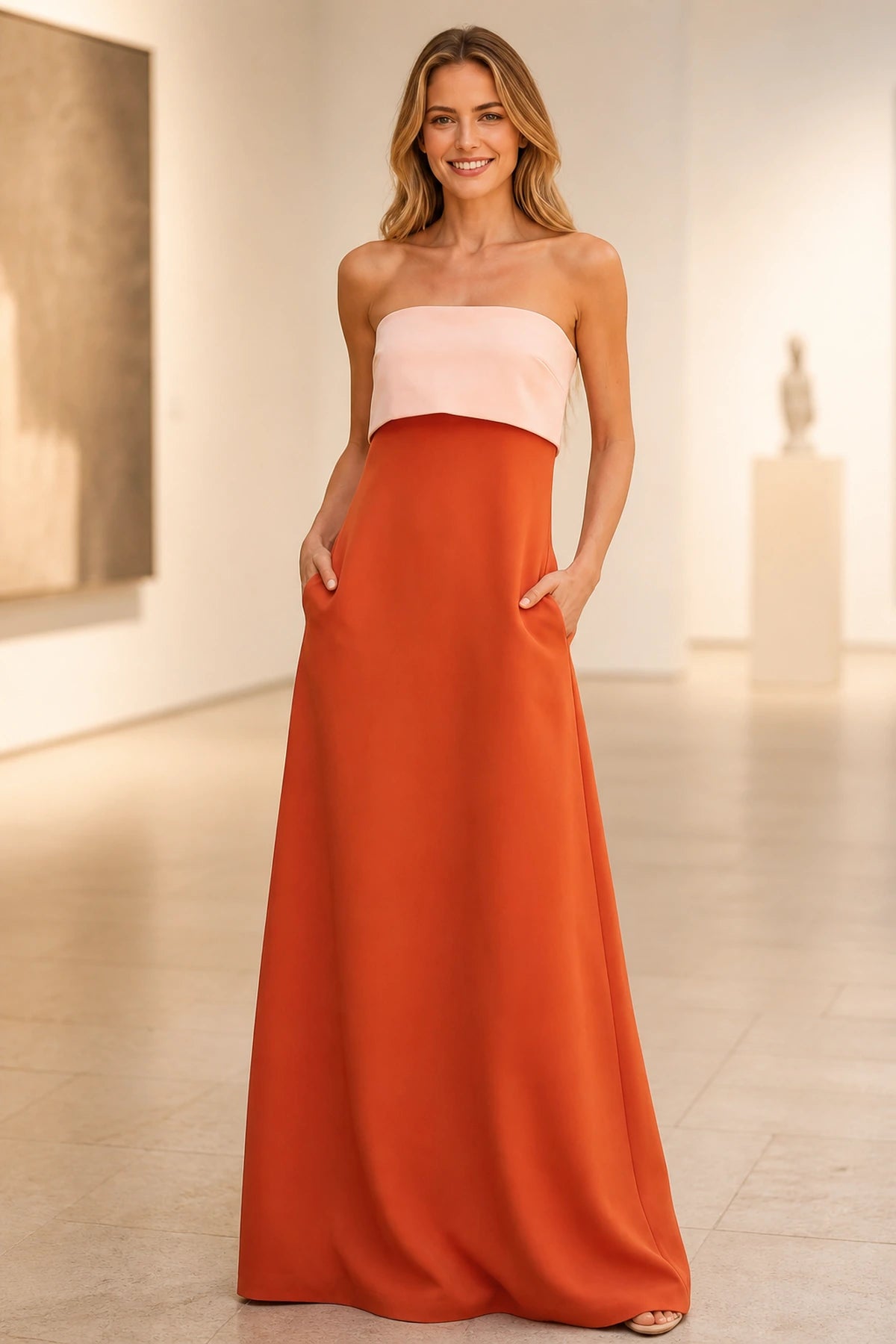 Two-tone strapless wedding guest dress with ivory overlay, burnt orange A-line skirt, side pockets and floor-length hem