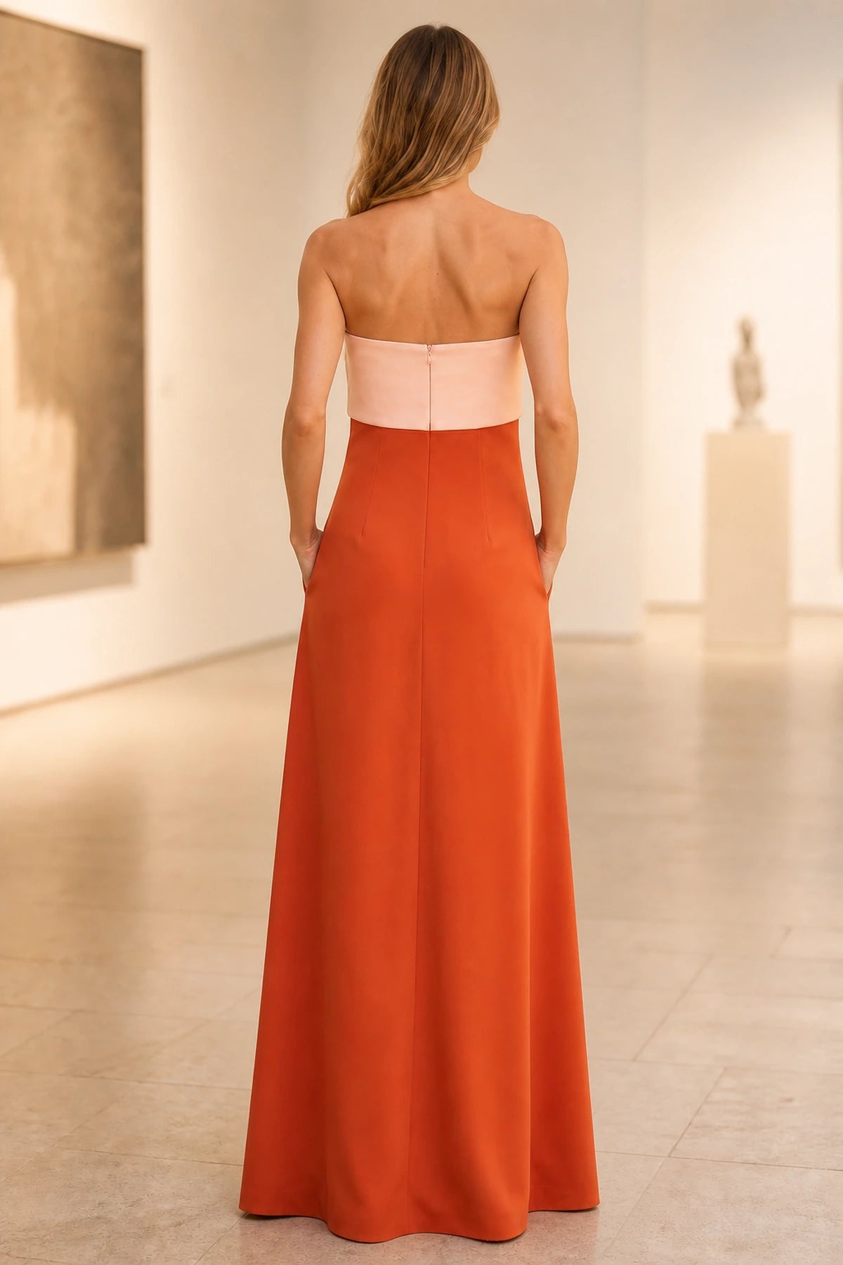 Back view of two-tone wedding guest dress with strapless straight back, center zipper and burnt orange floor-length A-line skirt